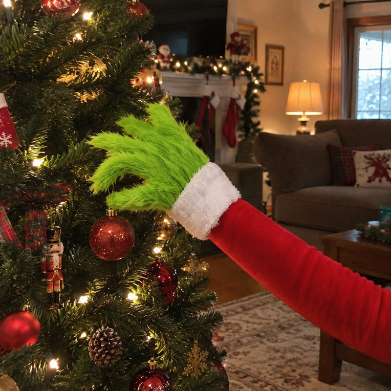 Furry green arm reaching out of a Christmas tree holding an ornament
