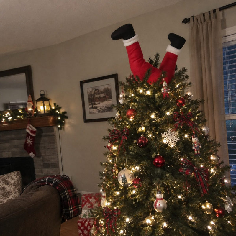 Santa legs sticking out of the top of a Christmas tree